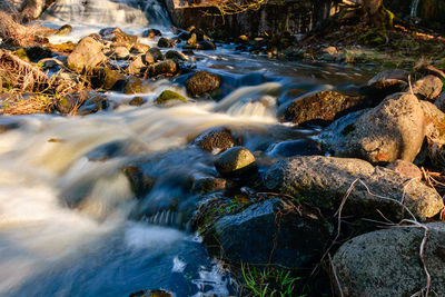 Rapid river flow between rocks, water white as milk, long-term exposure, spring in nature
