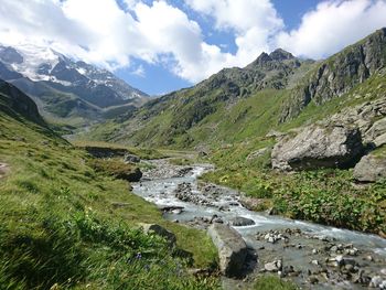 Scenic view of stream amidst mountains against sky