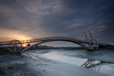 Bridge over river against sky during sunrise