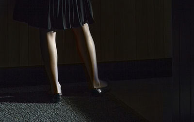 Low section of woman wearing shoes standing on carpet