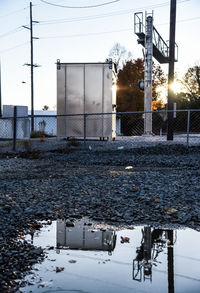 Reflection of electric box on puddle in street