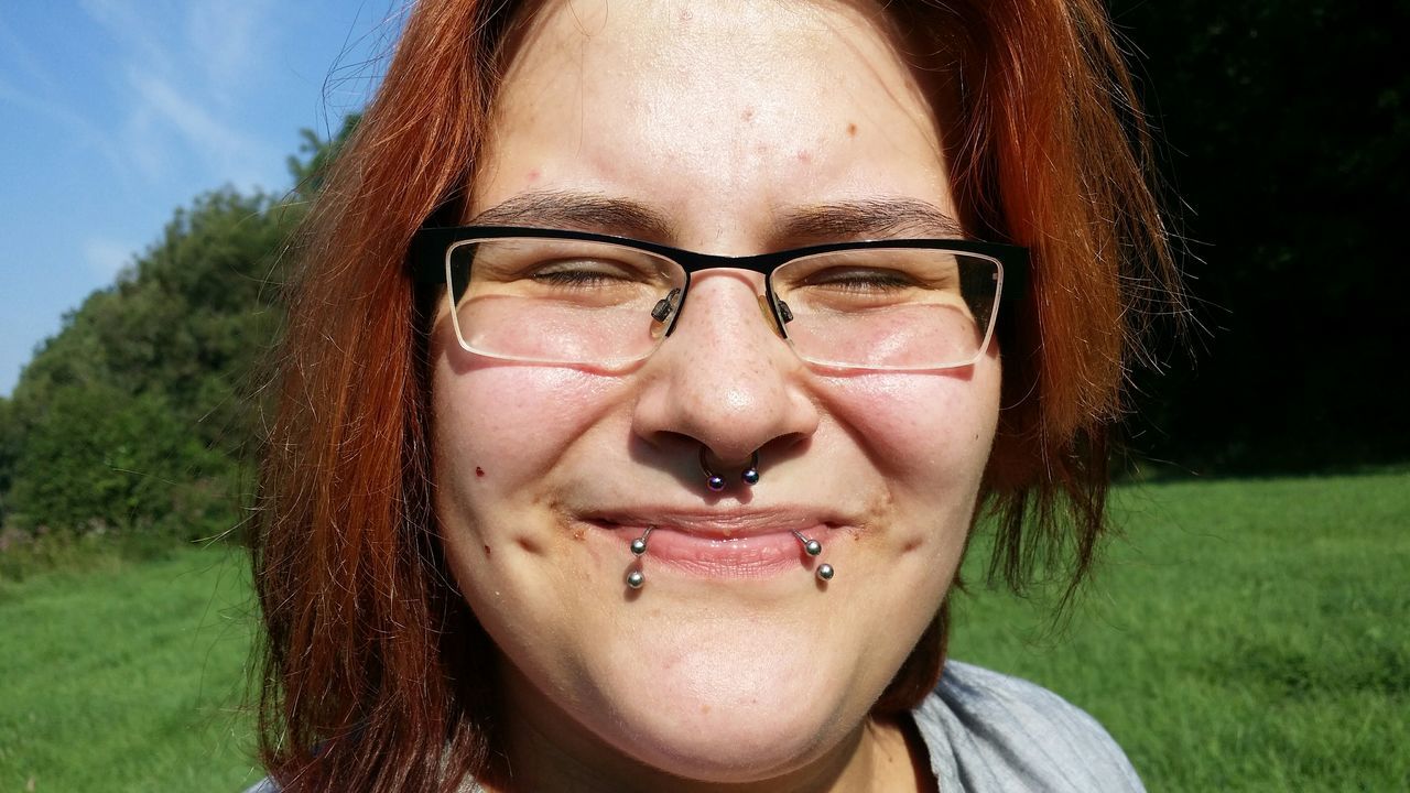 portrait, looking at camera, person, young adult, front view, headshot, lifestyles, smiling, leisure activity, close-up, young women, happiness, sunglasses, field, focus on foreground, toothy smile, grass, casual clothing