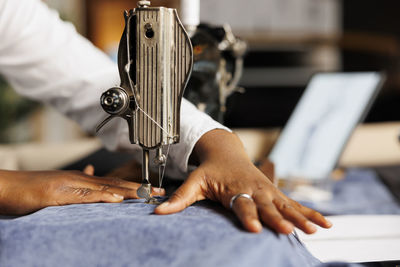 Cropped hand of man using sewing machine