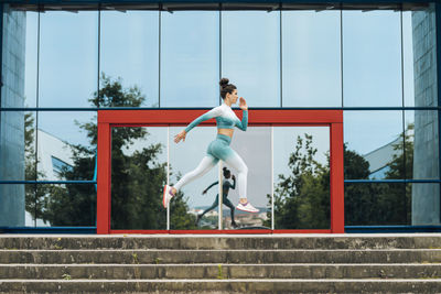 Active sportswoman running on steps by glass wall