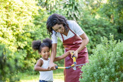 Full length of mother and daughter standing against plants