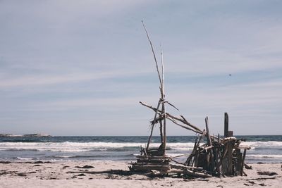 Damaged hut on shore at beach against sky