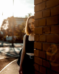 Portrait of woman standing by wall outdoors