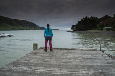 Rear view of man standing on pier over sea against sky