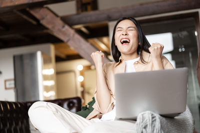 Portrait of young woman using mobile phone while sitting at home