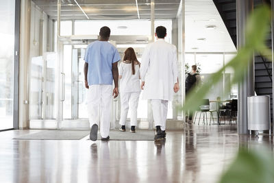 Full length rear view of healthcare workers walking in lobby at hospital