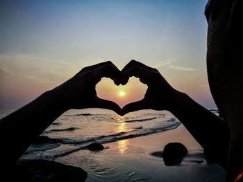 Close-up of silhouette man making heart shape against sky during sunset