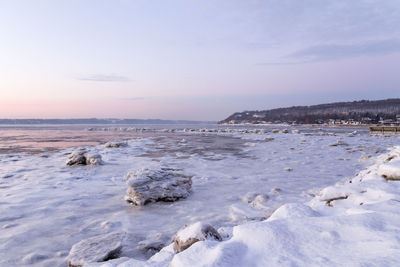 Boulders of ice scattered on the banks and on the partly frozen st. lawrence river seen at sunrise