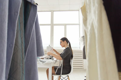 Side view of woman using phone while sitting at home