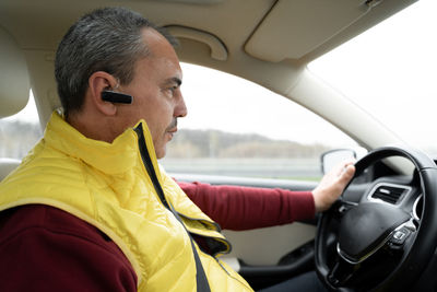 Side view of man using mobile phone while sitting in car