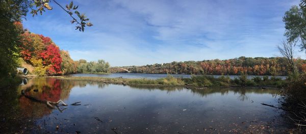 Scenic view of autumn trees by river against sky