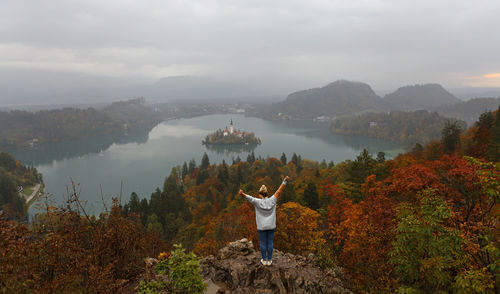 Rear view of woman standing on mountain by lake during autumn