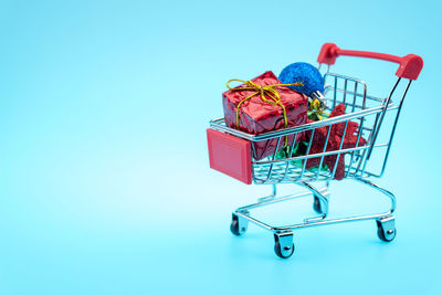 Close-up of christmas presents in shopping cart over blue background
