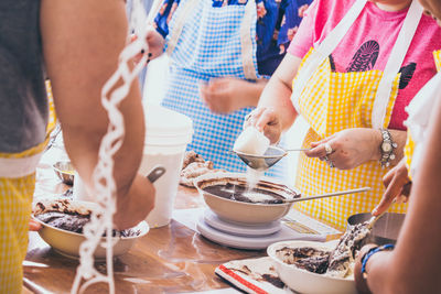 Midsection of people preparing food on table