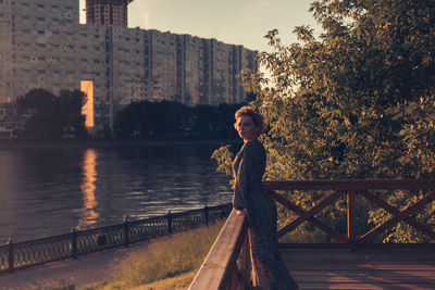 Portrait of woman standing by railing against lake