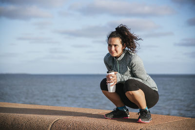 Girl drinking water by the sea