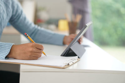 Midsection of woman reading book on table