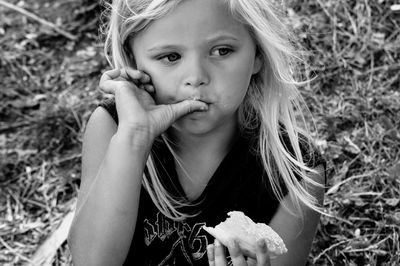 Girl looking away while eating food on field