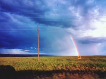 Rainbow over field against sky