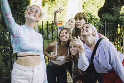 Happy woman taking selfie with friends gesturing and showing peace sign