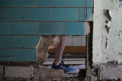 Low section of man standing by damaged wall