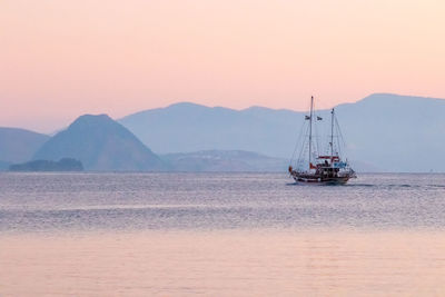 Sailboat sailing on sea against clear sky during sunset