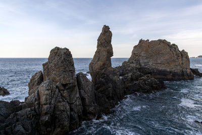 Rock formation on beach against sky