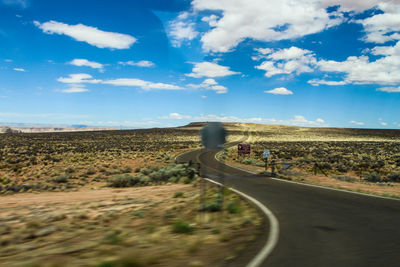 Road leading towards landscape against sky