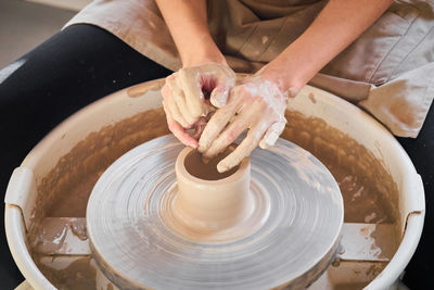 Cropped hands of potter making earthenware at pottery workshop