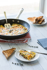 Bacon and asparagus frittata in a frying pan with one serving in front.