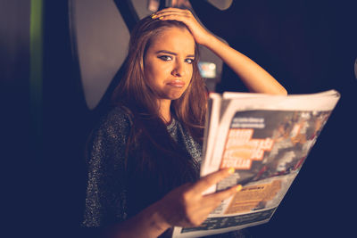 Portrait of sad young woman with magazine at home