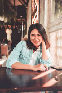 Portrait of smiling young woman sitting on table