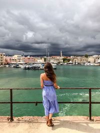 Rear view of woman standing on promenade at harbor