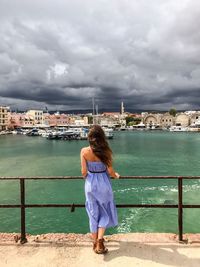 Rear view of woman standing on promenade at harbor