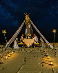 Couple sitting under tent against sky