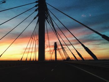 Silhouette of suspension bridge against cloudy sky