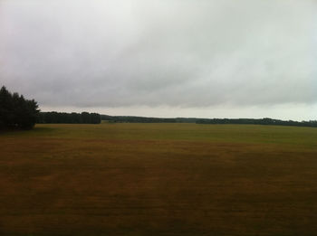 Scenic view of field against cloudy sky