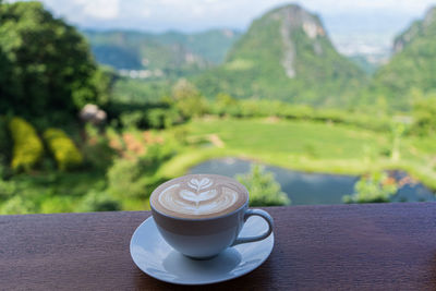 Coffee cup on table against mountains