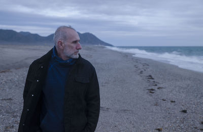 Adult man in winter clothes on beach during sunset. almeria, spain