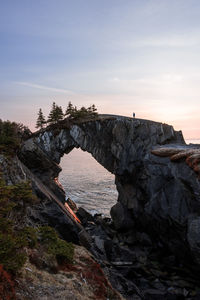 Man hiking at berry head arch at sunrise, along the east coast trail of newfoundland, canada