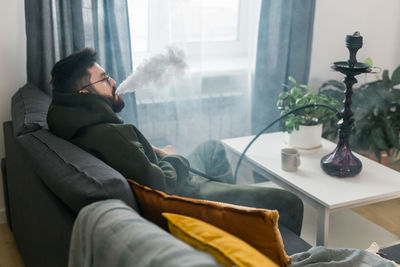 Rear view of woman sitting on bed at home