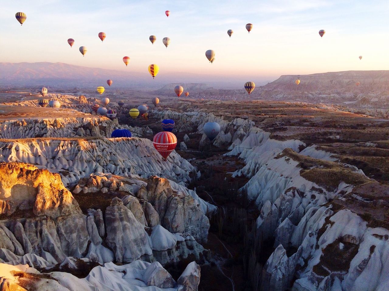 flying, mountain, scenics, mid-air, landscape, beauty in nature, sky, tranquil scene, sun, tranquility, nature, rock - object, sunset, rock formation, sunlight, hot air balloon, travel, mountain range, physical geography, idyllic