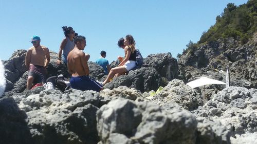 Low angle view of people on mountain against clear sky