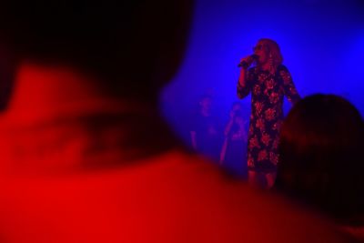 Midsection of woman standing against illuminated wall at night