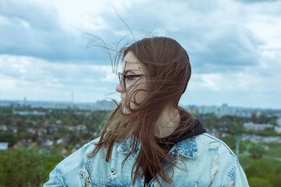 Portrait of young woman looking at camera against sky