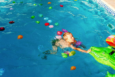 High angle view of boy playing with toys swimming in pool